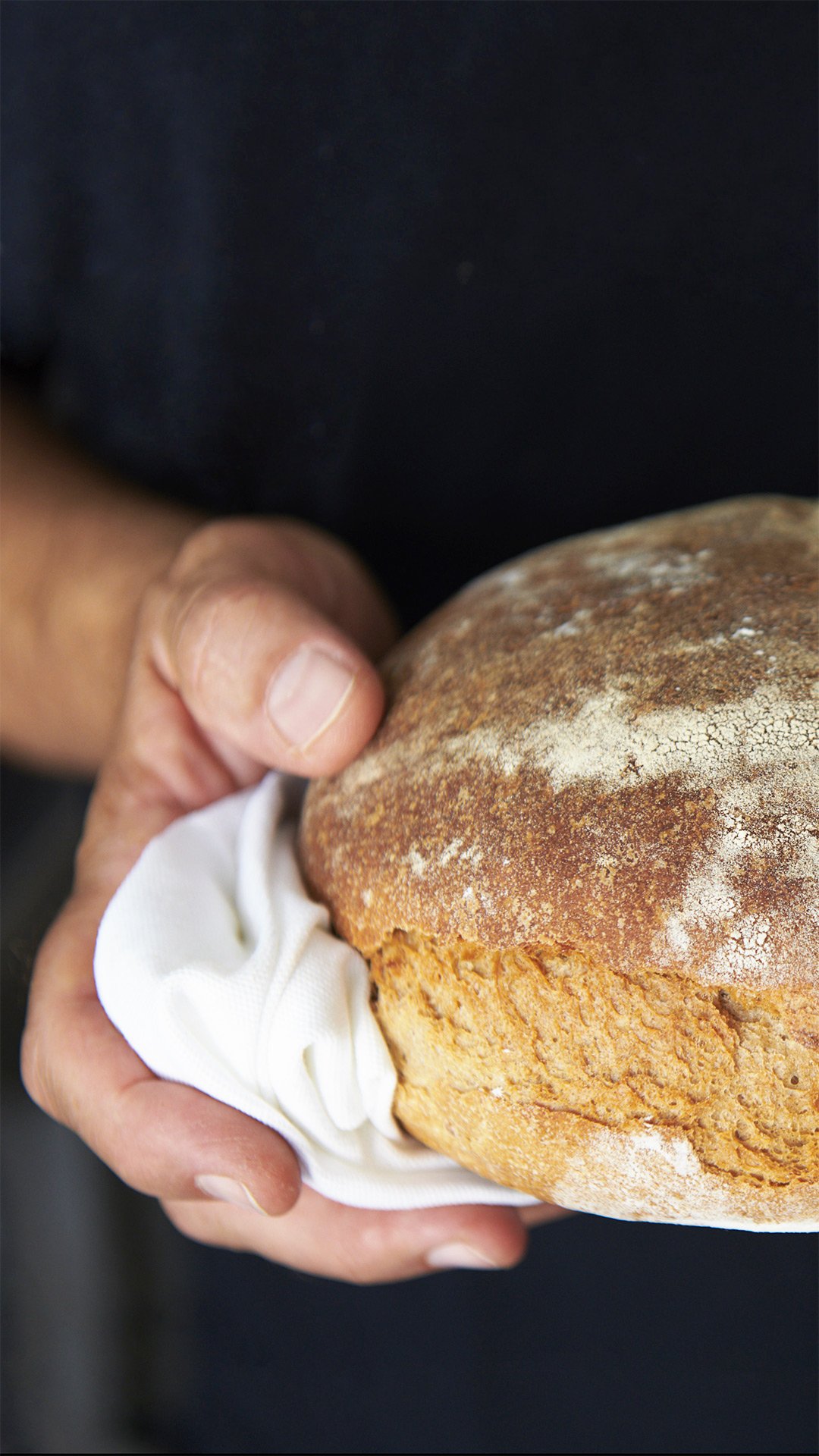 Ein frisch gebackenes Brot wird mit zwei Händen gehalten